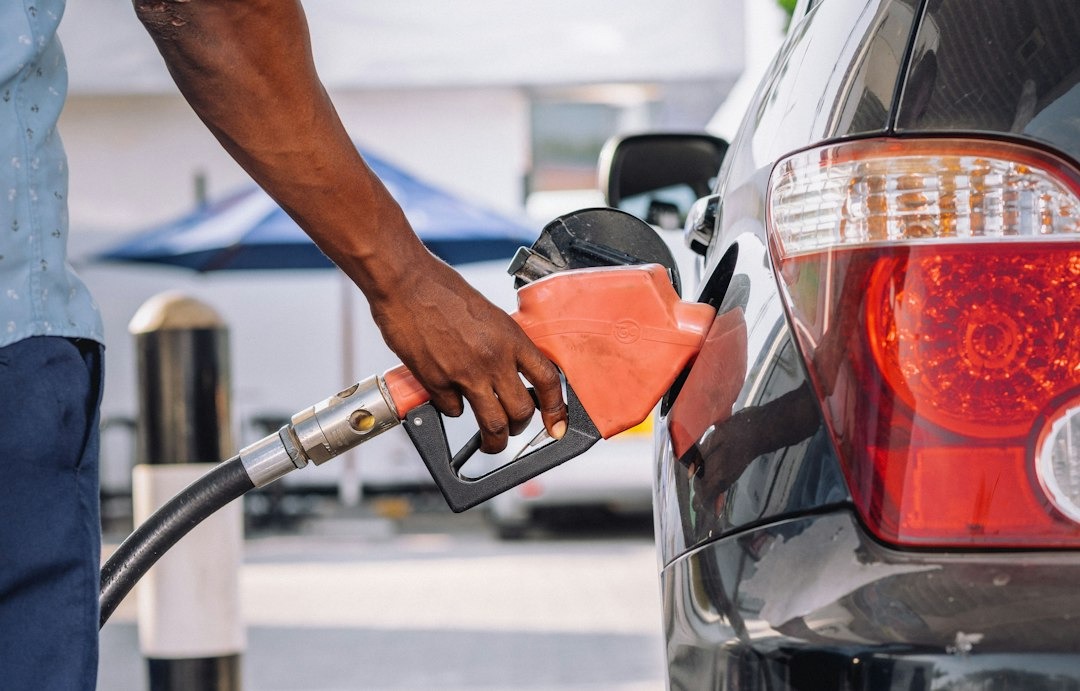 Man pumps gas into a dark car at a gas station.